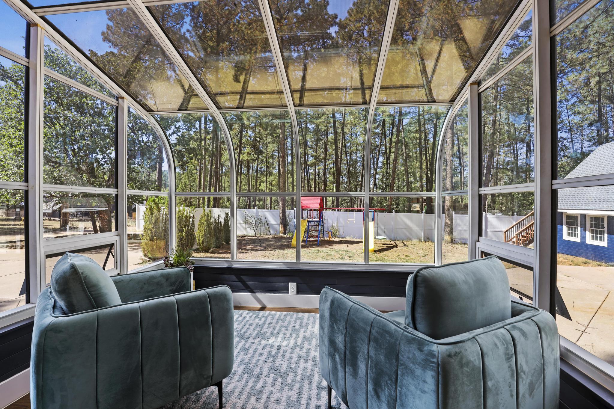 Glass solarium with two lounge chairs overlooking the property
