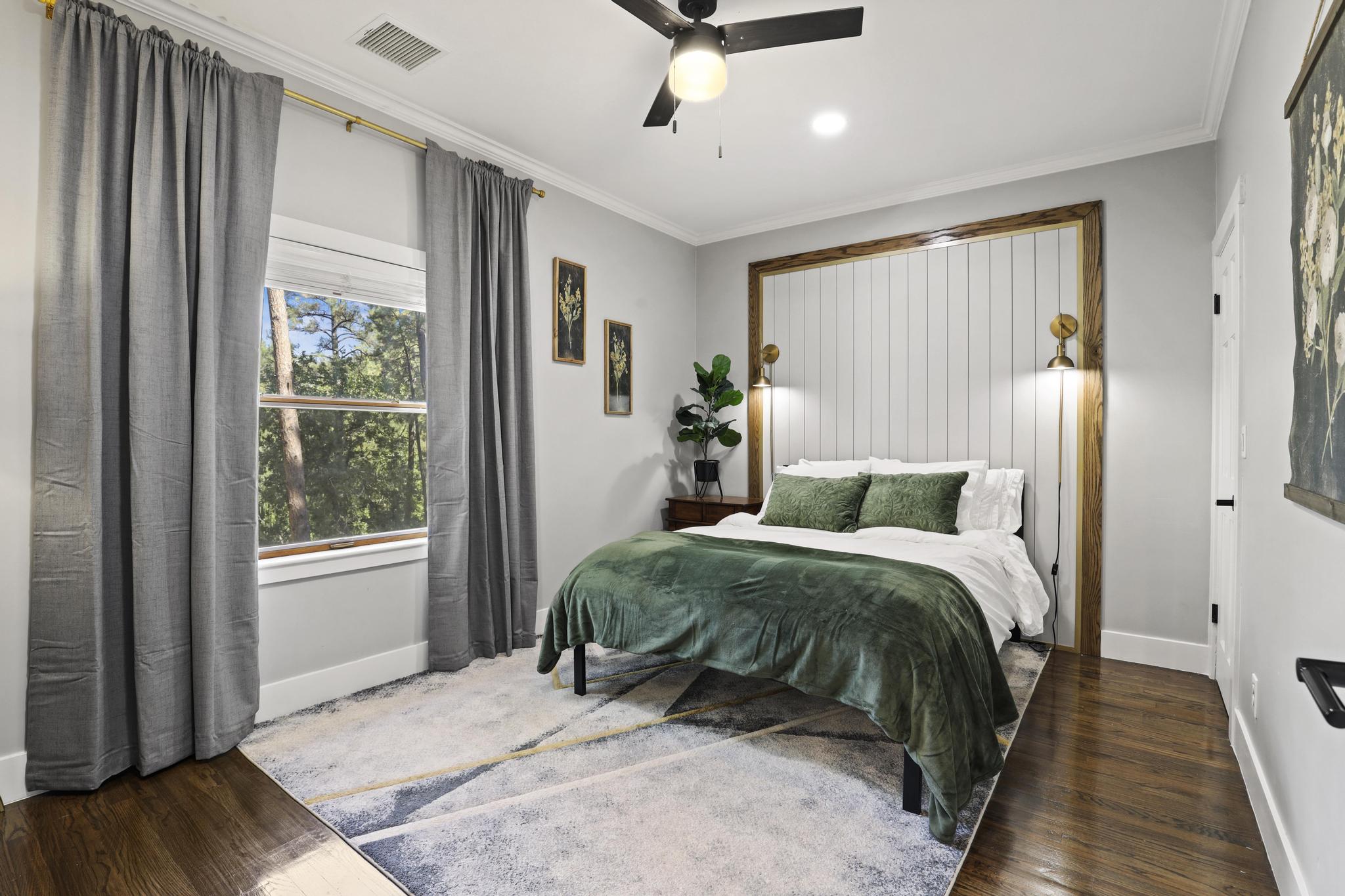 Bedroom with green bedding, wood-framed headboard, and pine views