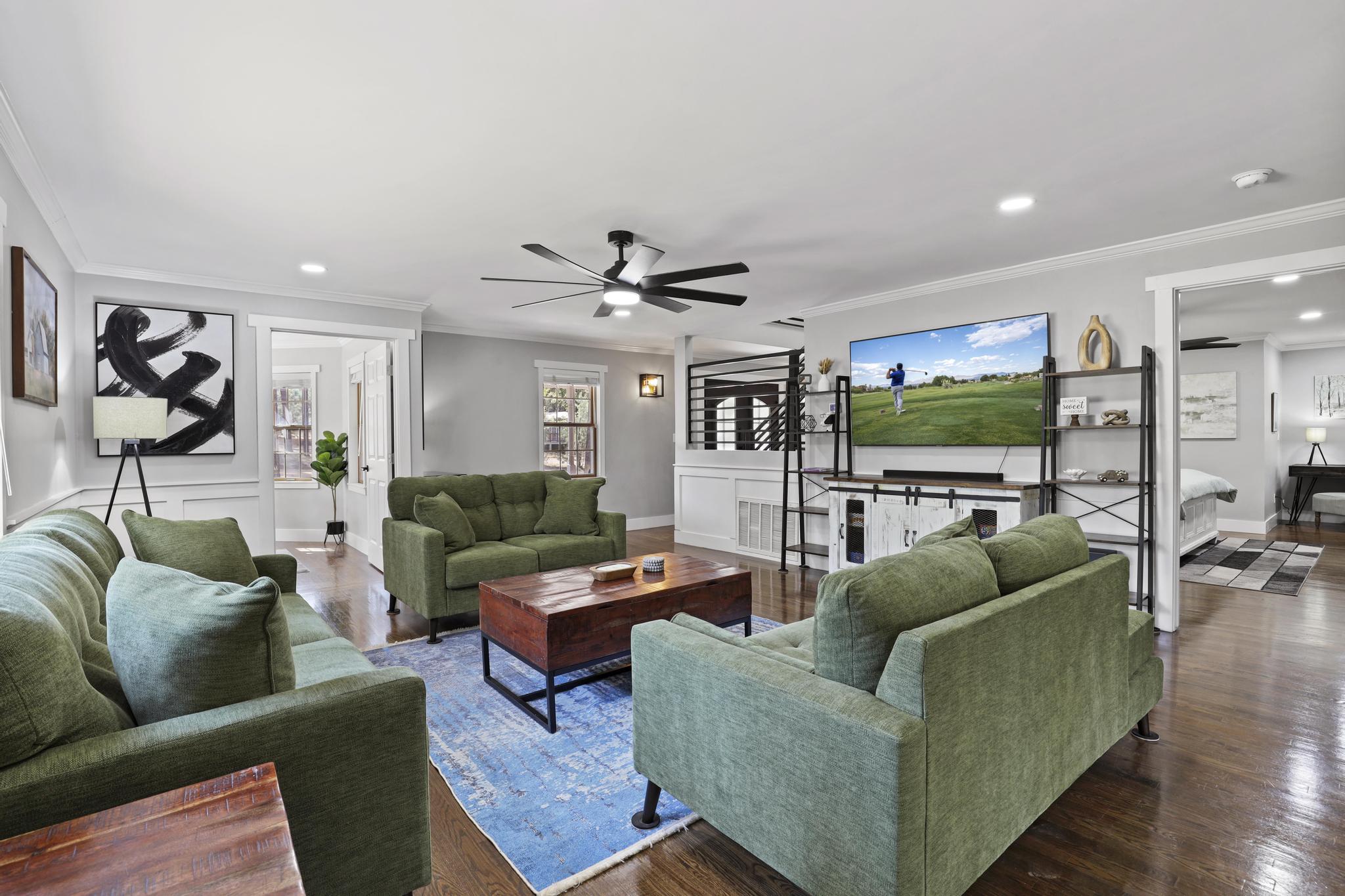 Living room with green seating and wide open flow to adjacent spaces