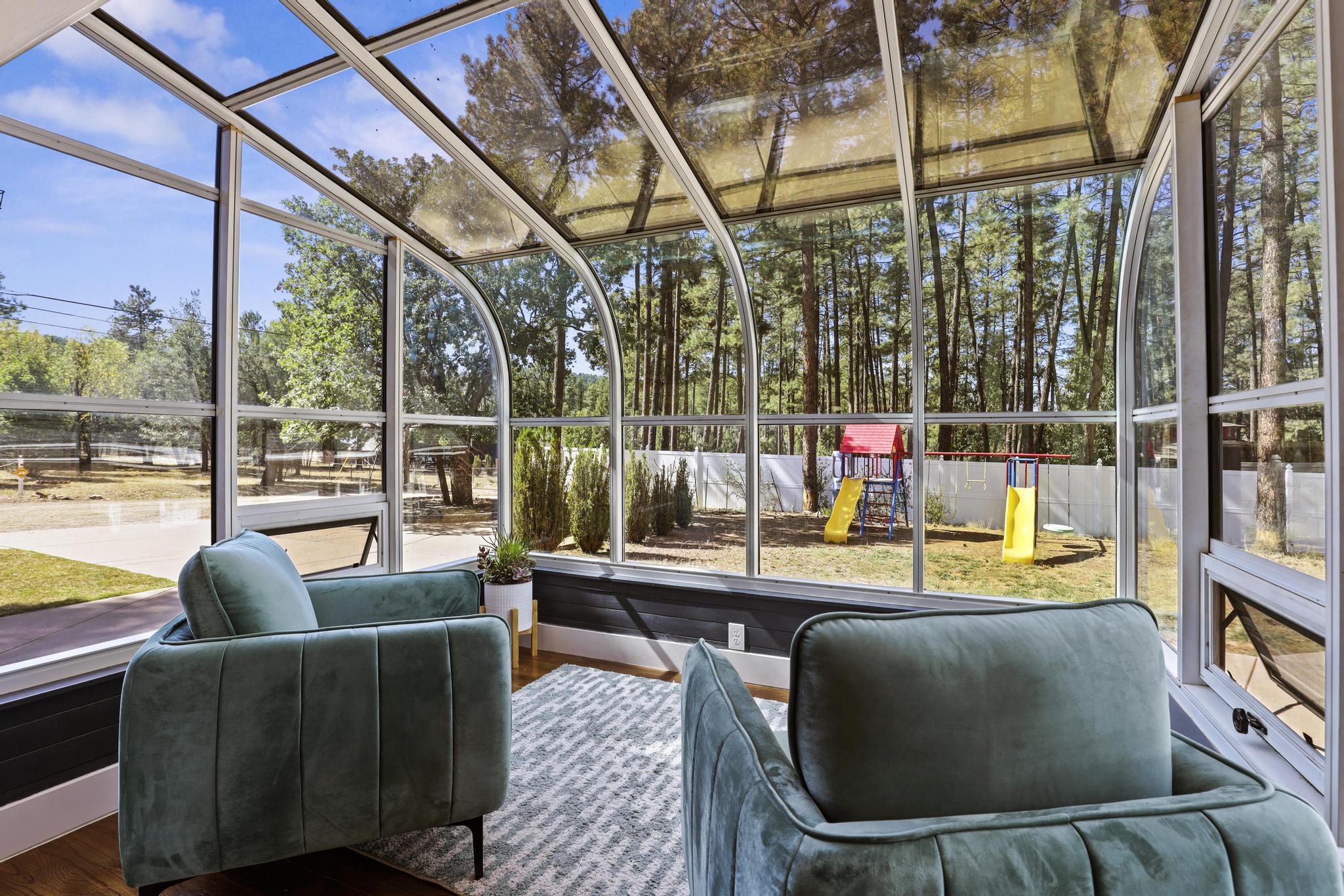 Glass solarium with blue chairs and panoramic pine views